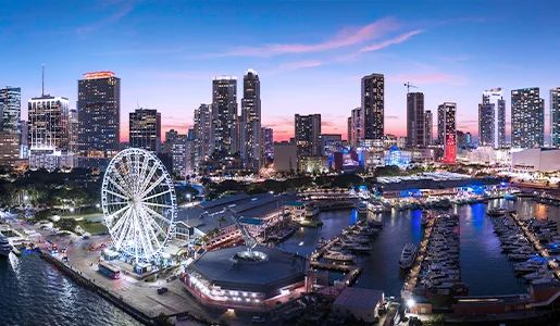 Miami skyline at sunset with ferris wheel and marina.